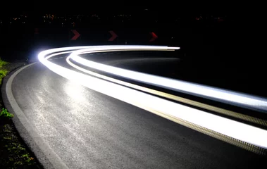 Mesmerizing long exposure shot capturing the light trails of cars speeding through a curvy road at night, symbolizing motion and energy in a modern setting.