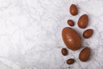 Easter chocolate egg on textured background. Easter celebration concept. Easter chocolate rabbit. Chocolate sweet eggs. Candies on textured wooden table. Space for text.Copy space. Gift. Banner.