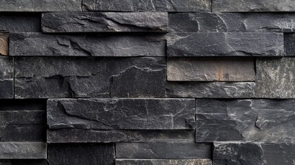 Textured black brick wall showcasing rough surfaces and unique imperfections, creating an industrial and rustic ambiance with layered stone patterns.