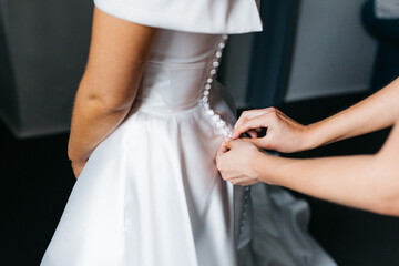 Brides wedding dress being buttoned up by bridesmaid