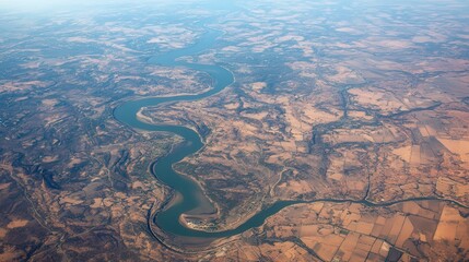 Aerial view of a winding river amidst arid landscapes and agricultural fields.