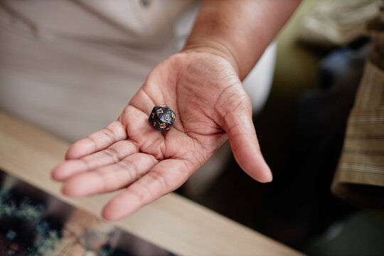 Close up of senior woman holding dice in open palm while playing board games with friends copy space - Powered by Adobe