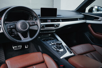 Modern brown car interior, leather steering wheel, climate control, navigation, air ducts,...