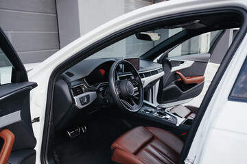 Modern brown car interior, leather steering wheel, climate control, navigation, air ducts, deflectors on the car panel, interior details.