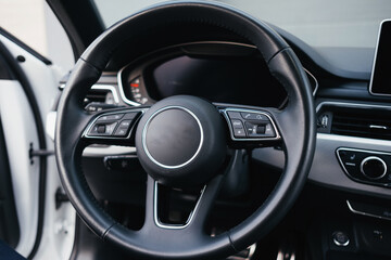 Modern brown car interior, leather steering wheel, climate control, navigation, air ducts, deflectors on the car panel, interior details.