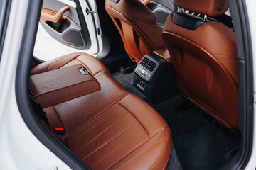 Modern brown car interior, leather steering wheel, climate control, navigation, air ducts, deflectors on the car panel, interior details.