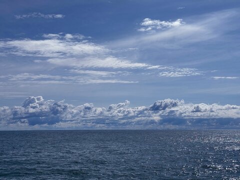 Beautiful sky clouds over blue shiny ocean 