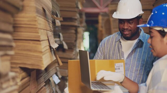 African man worker and asian woman recheck stock at paper factory.