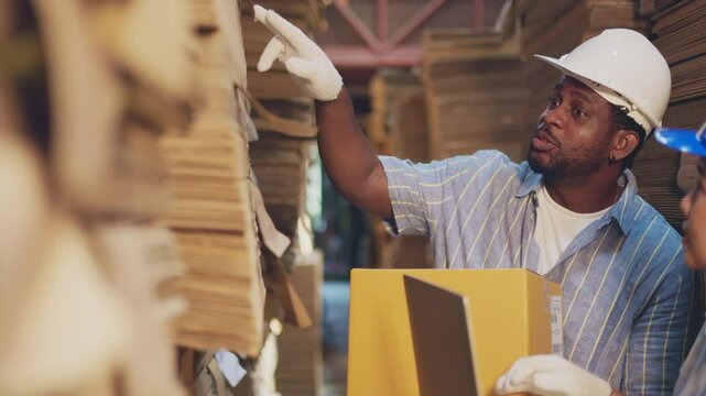 African man worker and asian woman recheck stock at paper factory.