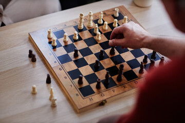Top view close up of unrecognizable man playing chess with focus on hand moving pawn piece copy space