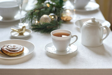 White cup of tea on Christmas celebration dinner table on the white linen cloth.