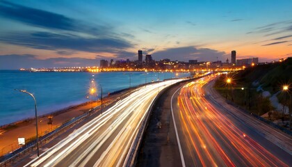 The motion blur of a bustling urban highway during evening rush hour captures the vibrant city energy, with glowing car lights streaking against a stunning skyline backdrop in the fading