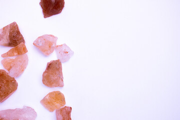 A pile of pink rocks on a white background. The rocks are of different sizes and shapes, and they appear to be arranged in a random pattern. 