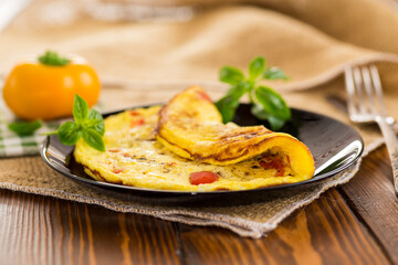 fried omelette with sweet pepper and vegetables in a plate on a wooden table