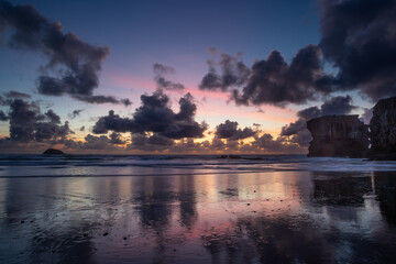 Fototapeta premium Stunning Muriwai Beach covered with clouds at sunset