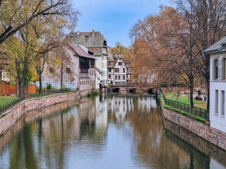 Obraz premium Picturesque river view in La Petite France in Strasbourg with half-timbered houses and water reflection, Colourful architecture, canal and blue sky in November, Travel destination, Alsace, France