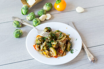 Brussel sprouts cooked with vegetables and spices, on a wooden table