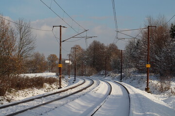 Winter landscape with snow covered rails on a road railway in a snowy scene on the horizon
