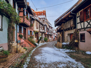Eguisheim - Charming, colorful, snowy cobblestone street with half-timbered houses in snow and colorful facades, beautiful village near Colmar, Alsace region, France Travel destination in November