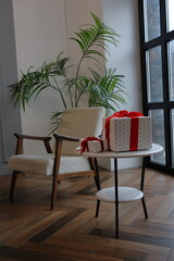 New Year's decor, Christmas gift in the living room on table. an armchair and gift box on Christmas Eve. holidays, traditions.