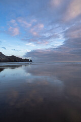 Gorgeous sunset clouds reflections at the Te Henga surf beach, Auckland, New Zealand