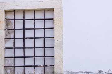 Fototapeta premium Opening in the wall in the old house is covered with a metal grate and plastered stone