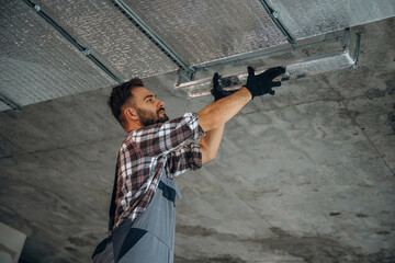 Installing the ceiling. A man is renovating an unfinished room