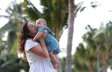 Naklejka premium Mother and her baby son playing on the beach during summer vacation