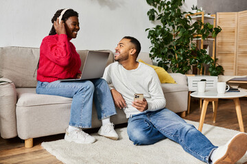 Fototapeta premium A joyful African American couple shares quality time at home while wearing warm sweaters.
