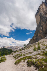 Hiking path through the Dolomites with towering cliffs and dramatic sky in Italy during summer