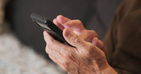 Hands of old man holding checking touching scrolling smartphone, close-up, side view