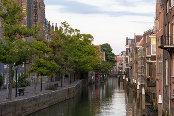 A picturesque canal scene with historic European-style buildings, a cobblestone pathway, and trees...