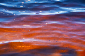 the water surface of a river or lake with sun glare at sunset