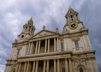 This dramatic stock photo captures the imposing front facade of St. Paul's Cathedral in London, UK, set against a backdrop of dark, swirling storm clouds. 