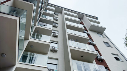 Photo of Low-Angle View of a Modern Apartment Building with Glass Balconies and Air Conditioners