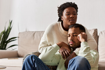 African American couple wearing cozy sweaters during winter, woman comforting her sad man