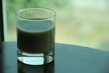 Transparent double wall glass, with black coffee, on white background. Cup with black liquid on white rotating table.