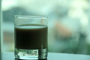 Transparent double wall glass, with black coffee, on white background. Cup with black liquid on white rotating table.