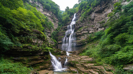 Cascading waterfall surrounded by lush greenery and rugged cliffs