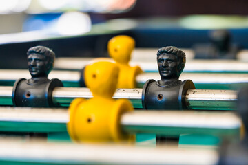 Close-Up of Yellow and Black Foosball Players on a Table with a Vibrant Green Background Highlighting Teamwork and Competitive Spirit