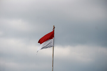 Indonesian flag fluttering in the wind with dark clouds in the background.