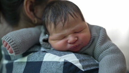 Close-up of a newborn baby resting on the mother&rsquo;s shoulder after breastfeeding, highlighting the peaceful and intimate bond between mother and child 