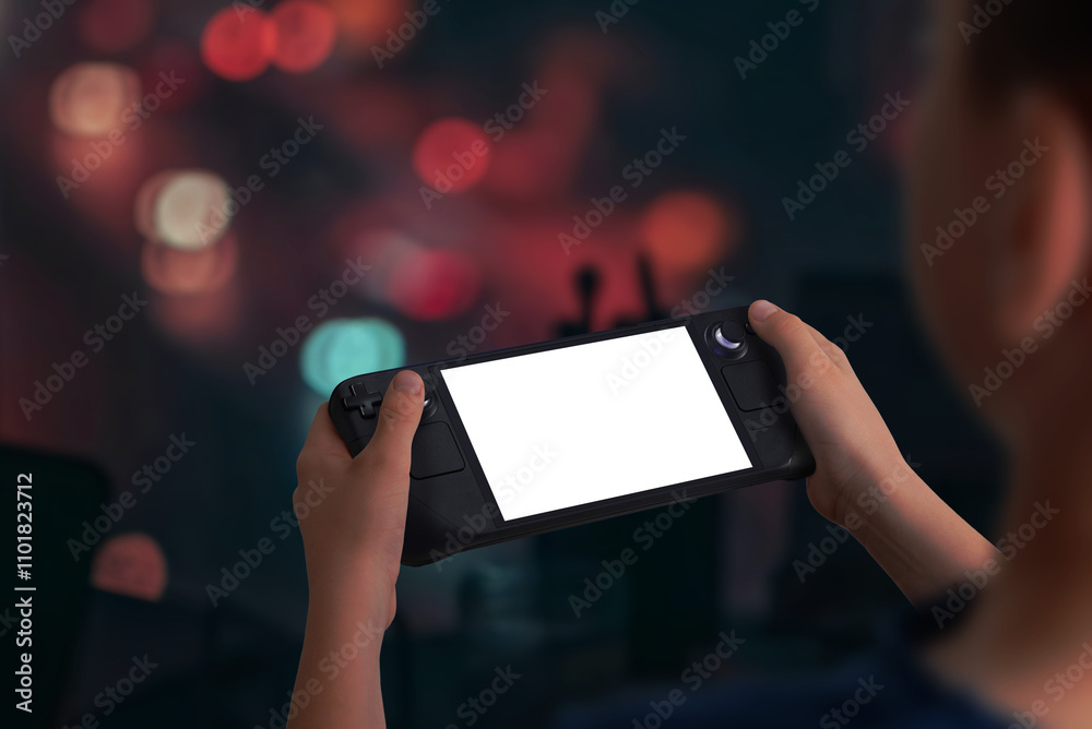 Poster boy holding a handheld gaming console playing a game in low light evening setting, perfect for mocku
