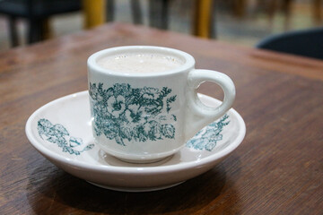 A glass of antique ceramic coffee cup on a teak wood table