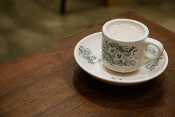 A glass of antique ceramic coffee cup on a teak wood table