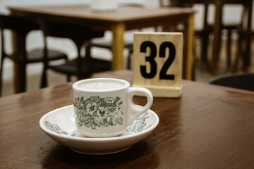 A glass of antique ceramic coffee cup on a teak wood table