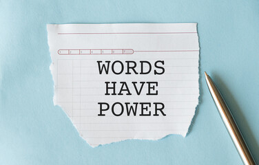 White paper with text Words have power lying on blue background.