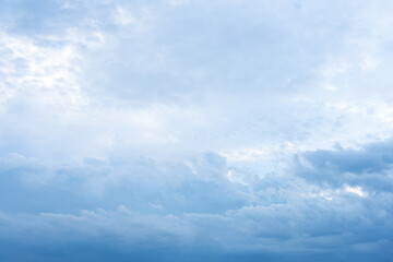 Fluffy white clouds drift across a vast expanse of clear blue sky