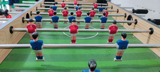 Group of friends playing kicker in sports bar room, teammates playing table football, table football game in office.