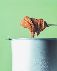 Homemade Creamy Chocolate Ice Cream. A frozen container contains a thick, creamy homemade chocolate ice cream that is stirred with a wooden spoon